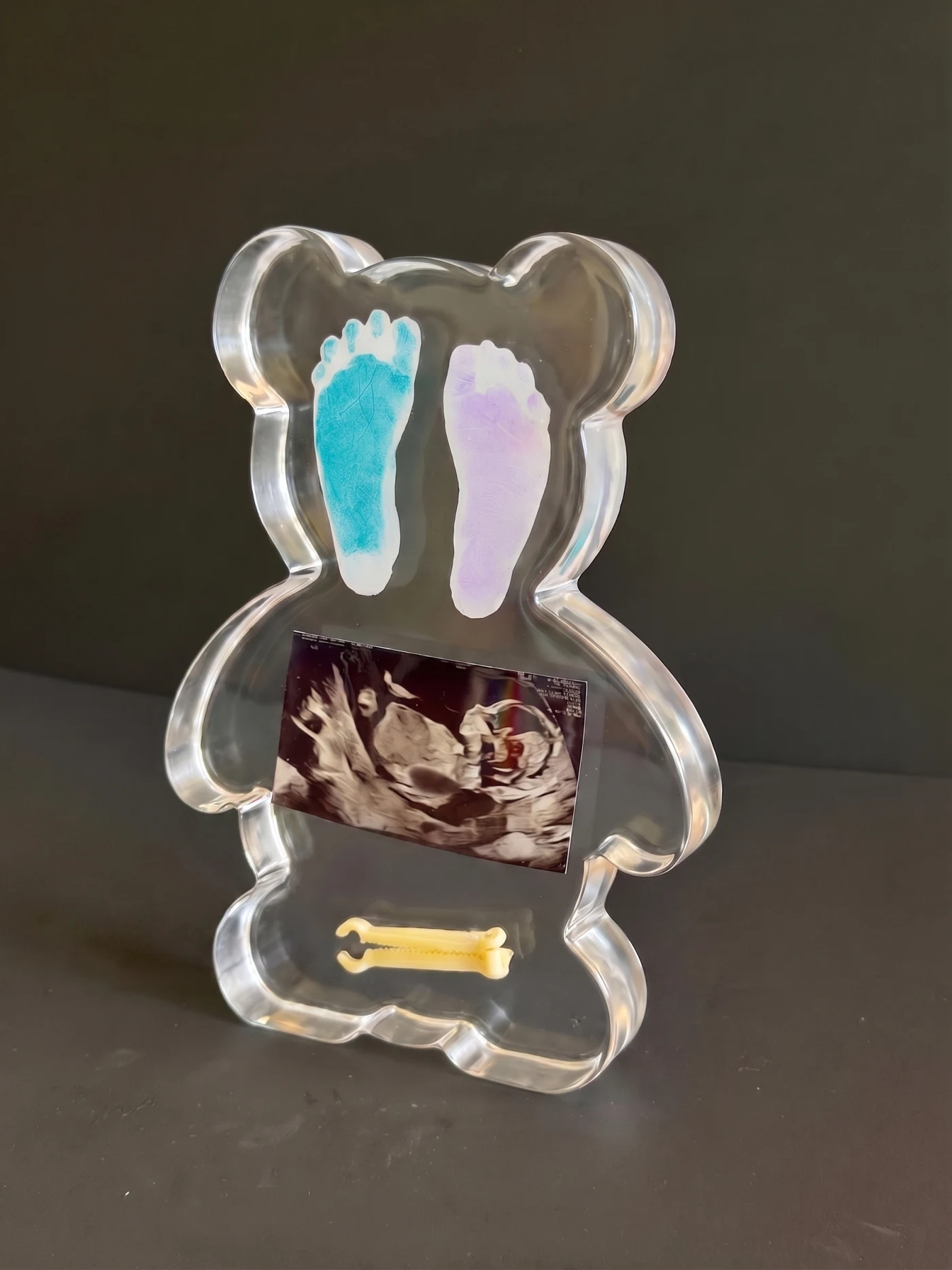 Front view of a clear resin teddy bear preserving footprints, ultrasound and cord clamp