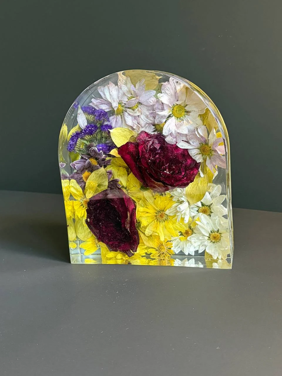 Front view of a clear resin arch preserving pale flowers